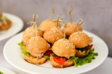 a plate of small burgers with sausage and tomatoes,fast food