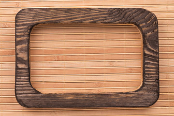 Beautiful one-piece dark wooden frame, lies on bamboo mat. Natural patterns