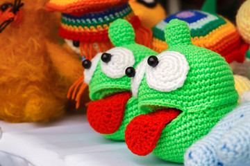 Colorful knitted handmade toys are on display for sale at a souvenir shop on the market. Close-up