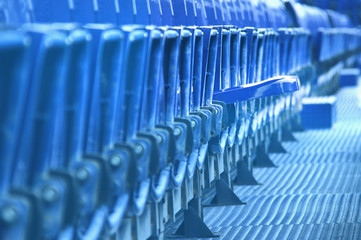 Dark blue metal empty seats in concert or football stadium,Row of seats in sport stadium.One seat is ready for fan.