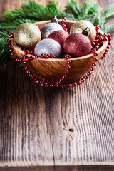 Christmas decorations balls fir tree red garland beads in a wooden bowl close-up.