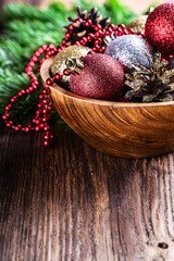 Christmas decorations balls fir tree red garland beads in a wooden bowl close-up.