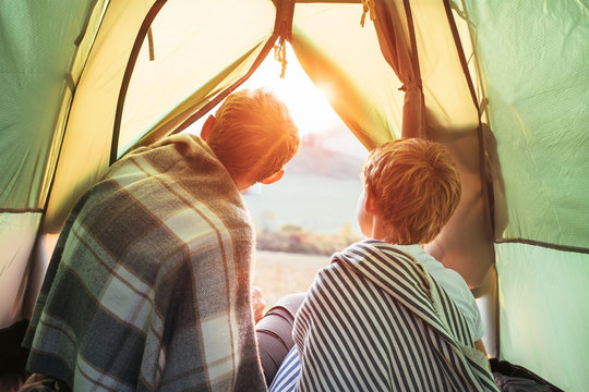 Father and son meet a sunset in mountain, look out from tent - Powered by Adobe