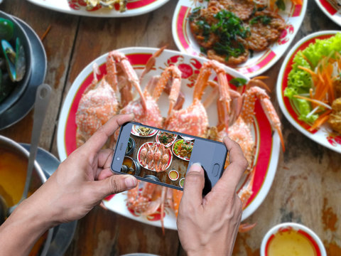 Human hand holding a smartphone photographing food