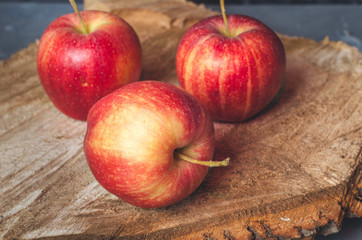 Three red apples on a wooden saw