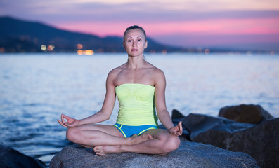 Fototapeta na wymiar Sportwoman meditating in yoga padmasana in evening