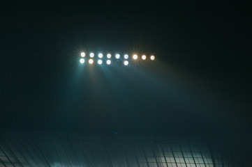 Hight lighter. Light tower lit at a football stadium during nigh time.