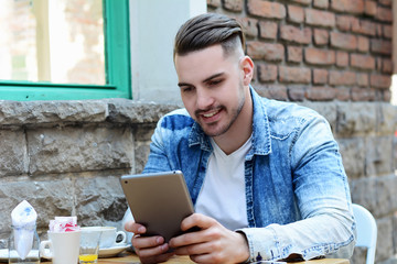 Young man in coffee shop cafe using a tablet.