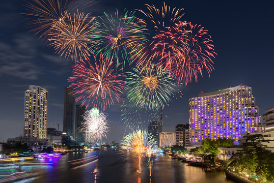 New Year Fireworks at midnight over clear sky above river city surrounding with luxury hotels, restaurants, condominiums, shopping mall in main city for special happy holiday celebration event