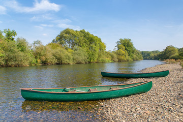 Two canoes lie on the bank of the river