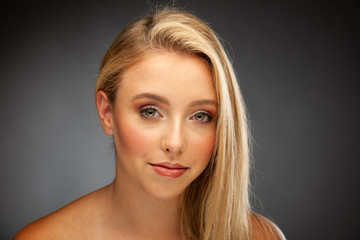 Makeup or skincare conceptual - beauty portrait of a young blonde woman with green eyes over dark...