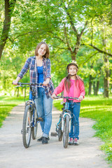 Mom and daughter are cycling in the park together