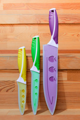 Close up Colorful Kitchen Knives with Different Purposes on Top of a Wooden Cutting Board, Captured...