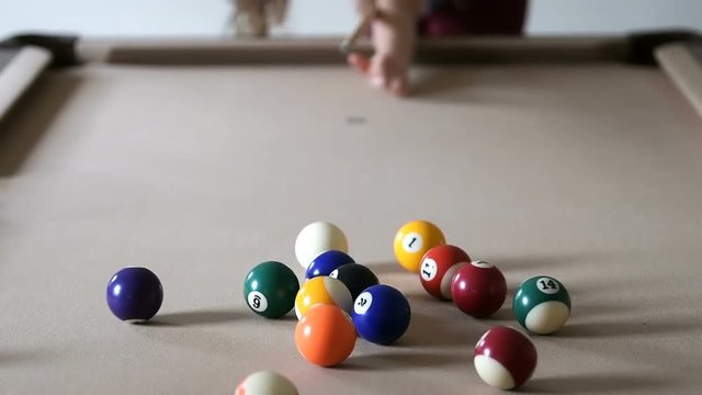 Slow motion of young woman bending over, aiming, pointing pool billiard cue at white ball, doing, taking break shot at home, house, apartment living, game room inside, indoors, indoor