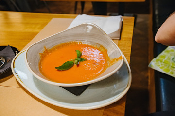 Tomato soup in a plate on wooden background.