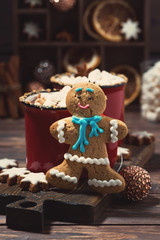 Obraz na płótnie Canvas gingerbread man cookies and hot chocolate on wooden background, vertical