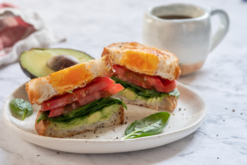 Egg in a hole sandwich with avocado, spinach and tomato