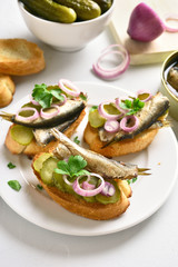 Sandwiches with sprats, marinated cucumber and onion