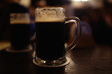 mug of dark beer in the interior of  pub / pint of beer with foam on a served table in  beer restaurant in Czech Republic