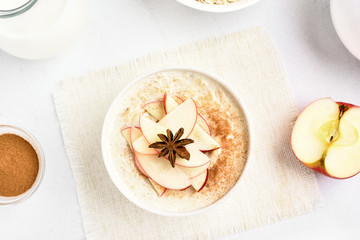 Fototapeta na wymiar Oats porridge with red apple slices and cinnamon