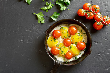 Fried eggs with tomatoes in frying pan