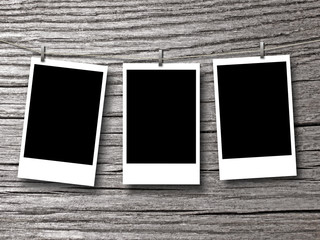Three blank rectangular instant photo frames against grey wooden background