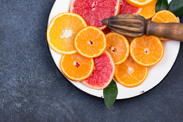 Fresh oranges, grapefruits and madarine slices on dark stone background.