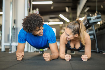 Beautiful young couple working out at the gym doing planks