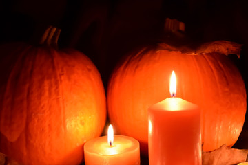 Halloween. Pumpkins, candles, autumn leaves on a black background. Scenery to celebrate Halloween.