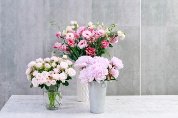 Roses, peonies and lisianthus (eustoma) on grey wall background