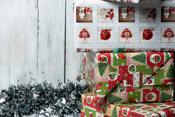 Christmas presents wrapped in green, red and white paper, decorated with ribbons, on a light, rustic wooden background