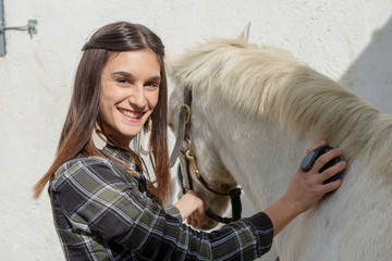 young woman rider brushing the white horse