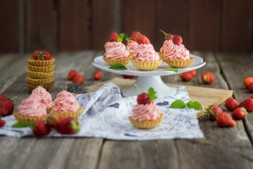 Strawberry tarts with strawberry whipped cream on set table.