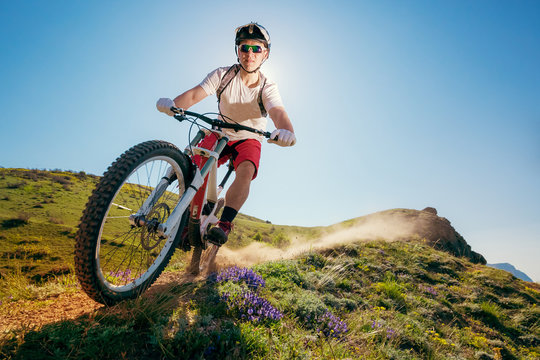 Mountain bike. Man riding bicycle on a dusty trail. Downhill.