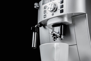 Close up of modern coffee machine and white cup at black background