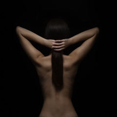 Healthy spine and hair of young woman on black background. Low key