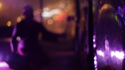 Soft focus bold man silhouette playing hanging gong by hammering with a soft hammer city lights bokeh in the background - Powered by Adobe