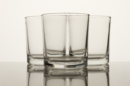Crystal clear glass cups on white. Close up. Reflective surface.