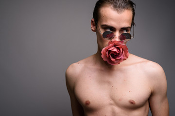 Young handsome man shirtless with flower in mouth