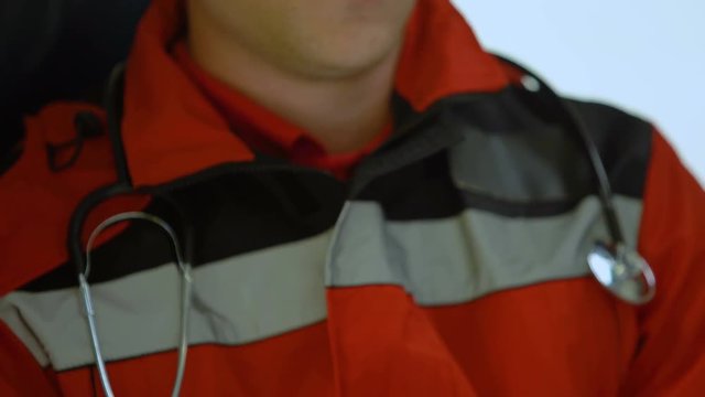 Male doctor responds by radio in ambulance, urgent call to car accident, closeup