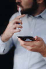 close up of man using smartphone. concept of phone addiction. young business man typing and browsing social media on his phone while brushing his teeth. 