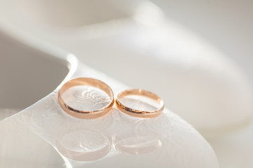 Two gold wedding rings on the background of the bride's shoes