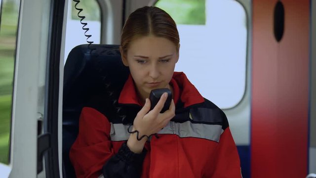 Female Paramedic Talking By Radio, Closing Ambulance Door To Drive Out On Call