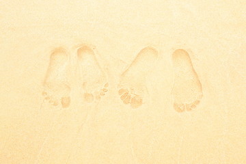 Fototapeta na wymiar Footprints in the sand pair of legs of a guy and a girl