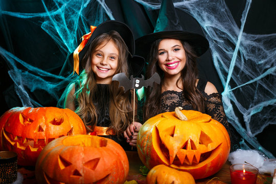 Happy Halloween. Mother and her daughter in witch costumes having fun at home.