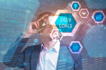 Business, Technology, Internet and network concept. Young businessman working in virtual reality glasses sees the inscription: 2019 goals