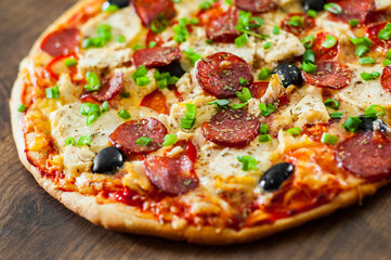 Pizza with Chicken meat, Mozzarella cheese, pepperoni, tomato, olive, salami. Italian pizza on wooden background