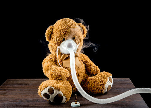 Steam mist from Nebulizer or nebuliser electrical machine drug delivery device used to administer medication in the form of a mist inhaled into the lungs concept. Toy teddy bear with face mask.