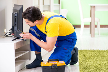 Male professional serviceman repairing tv at home