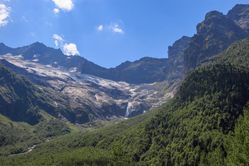 Closeup view mountains scenes and far away waterfall in national park Dombai, Caucasus, Russia, Europe. Summer landscape, sunshine weather and sunny day